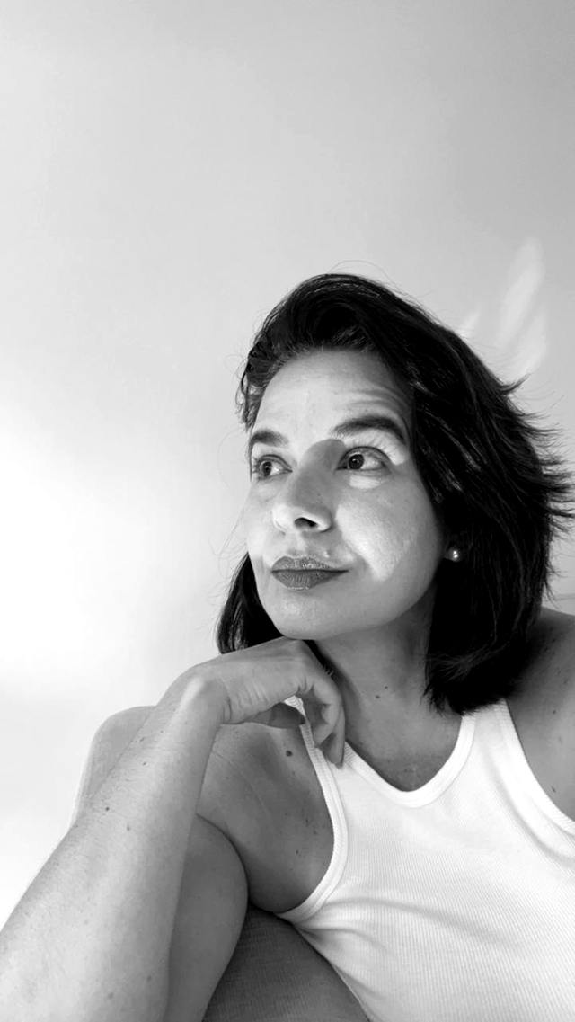 Tahís de regata branca, perfil calmo, queixo no punho